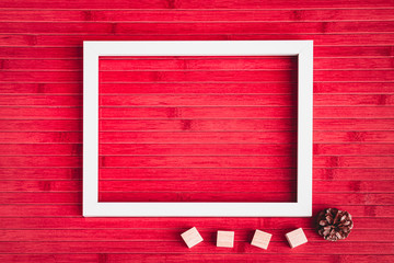 Happy Valentines Day with Empty white Photo Frame, Cube Boxes, Pine Cone on Red Wooden Table in Background