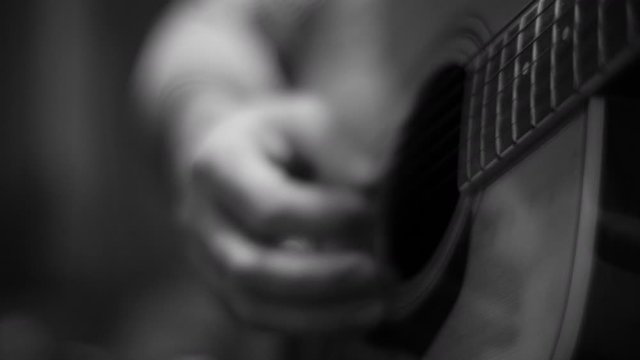 Musician playing acoustic guitar slow track in to hand strumming finish black and white