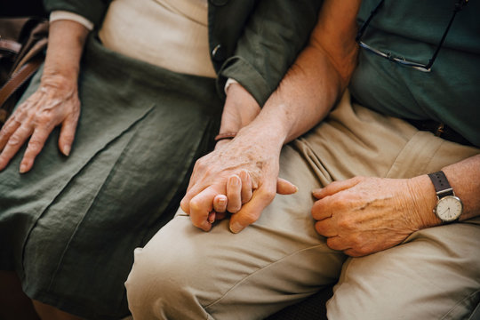 Midsection of senior couple holding hands sitting at nursing home