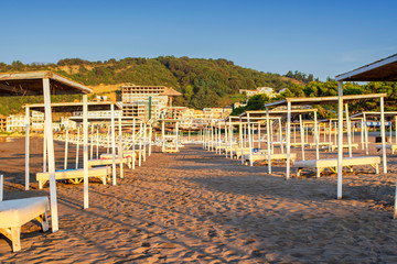Sun umbrellas and beach beds on the sea coast.Sun beds with a thatched roof on the seashore.