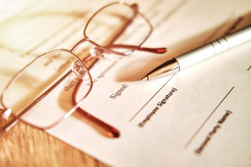 Fototapeta premium Contract sheet with glasses and a pen on a wooden background