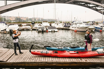 Senior male photographing female friends on jetty during kayaking course