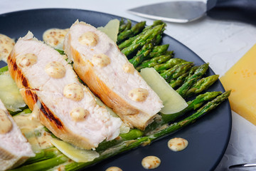 Freshly prepared turkey steaks, green asparagus with peanut sauce and parmesan cheese. Tasty diet recipe.