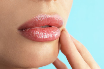 Woman with beautiful full lips on light blue background, closeup