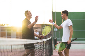 Father and Son Playing Tennis Outdoors.
