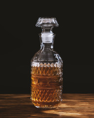 Whiskey decanter on wooden table on black background. Alcohol concept