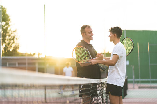 Father and Son Playing Tennis Outdoors.