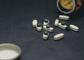 White and green pills on a black background