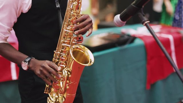 Afro american Musician playing saxophone on european city sidewalk close up