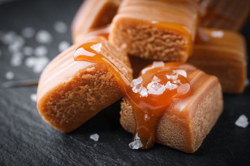 Salted caramel with sauce on black table, closeup view