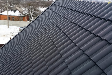 Installation of the roof of the house from ceramic black tiles.