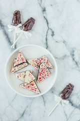 Peppermint white chocolate bark and chocolate suckers on marble background