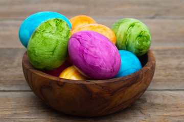 Easter colored eggs in a wooden bowl stand on a wooden table. Close-up. Easter holiday