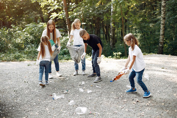Obraz premium Volunteers collects rubbish. Children in a park. Kids in a white t-shirts
