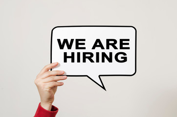 We are hiring text on speech balloon held by hand on light background.
