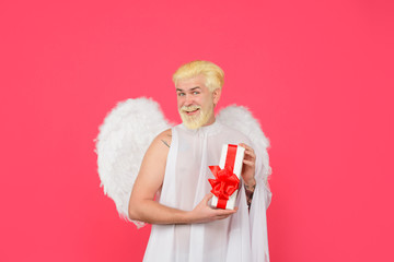 Obraz premium Valentines day angel. Cupid. Smiling man with angel wings. February 14. Cupid with gift. Love concept. Cupid with present box. Valentine angel. Cupid angel with present. Happy Valentines Day. Amour.