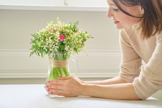 Woman Hands With Bouquet Of Flowers In Vase On Table
