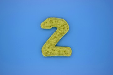 Number 2 is knitted from yarn on a blue background.