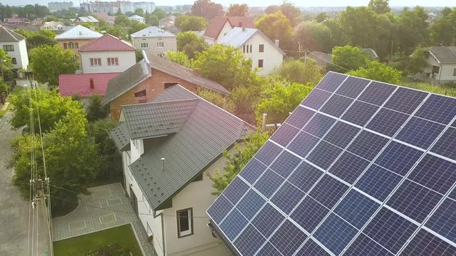 Aerial top view of new modern residential house cottage with blue shiny solar photo voltaic panels system on roof.
