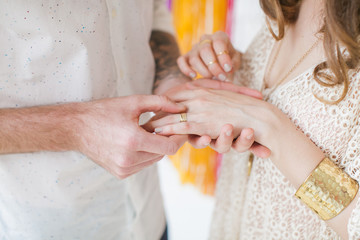 Wedding in boho chic style. Young married couple holding hands with golden rings.