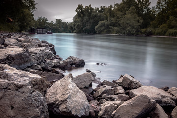 Large rocks near river shoreline, with trees in the background