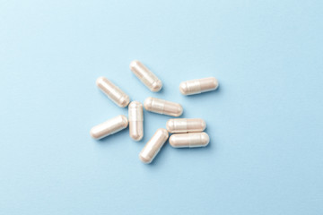 Carnitine capsules. Concept for a healthy dietary supplementation. Bright paper background. Close up. Top view. 