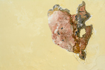Chipping yellow plaster paint on white stone wall