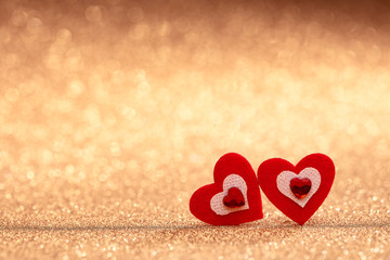 Two decorative hearts on a glittering gold background with copy space. Valentine's Day card.