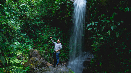 Man taking a selfie in the forest in front of the cascade