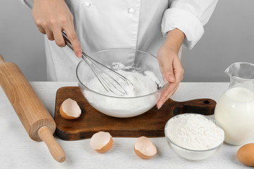 Woman whipping egg whites at wooden table, closeup. Baking pie