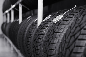 Fototapeta na wymiar Car tires on rack in auto store, closeup