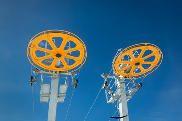Ski chair lift steel construction with big yellow wheels on beautiful winter day in ski tourist...