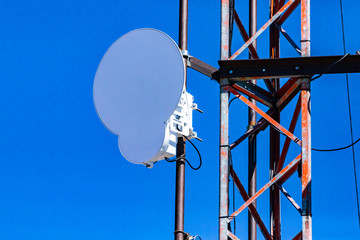 Closeup and detailed view of a circle microwave antenna fixed to steel lattice pylon. Emitting...