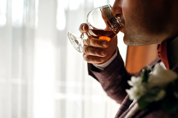 Stylish man with a glass of whiskey, an attractive man drinks cognac