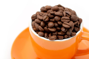 Roasted coffee beans in an orange cup