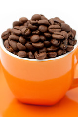 Roasted coffee beans in an orange cup