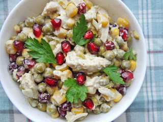 Salad with chicken breast, green peas, corn and pomegranate seeds dressed with low-calorie yogurt. Home salad with meat and vegetables. Top view, menu for a diet