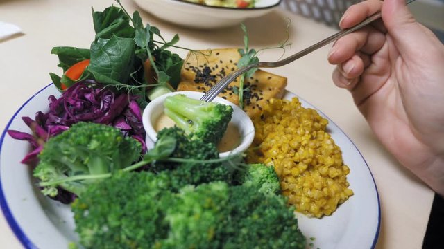 Beautiful fashion food design. vegetable bowl, man eats vegan food with a fork