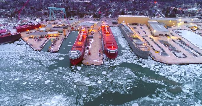 Giant Great Lakes freighter ships being built, refurbished, repaired, in icy cold waters, aerial view.