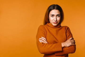 Young girl has cunning look and crossed her hands standing on the orange banner background