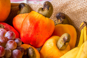fruits in wooden basket: cashew, orange, grape, banana, mango and papaya