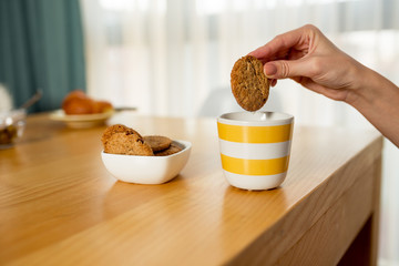 Unrecognizable woman eating cookies and milk for breakfast - Powered by Adobe