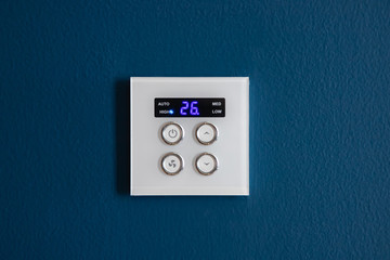 Modern digital programmable Thermostat for air condition on dark blue concrete wall. concept : smart house using technology.
