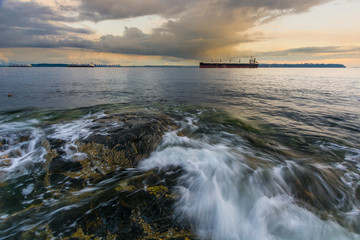 Obraz premium waves crashing on the shore with ship in background