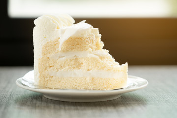 vanilla cake on plate and ice coffee on wooden table in cafe shop