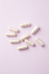 Carnitine capsules. Concept for a healthy dietary supplementation. Bright paper background. Top view. 