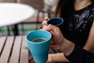Close-up of mugs in the hands of a young couple drinking coffee. Image of two cups of coffee held by the hands of two lovers