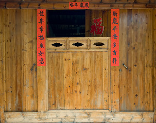 The old traditional style wood carving door with Spring festival couplets during Chinese new year.The text on scrolls  means Happy New Year and  Good luck and Peace all year round in Chinese