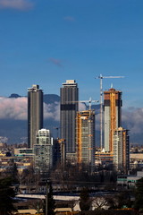 Fototapeta na wymiar New construction of high-rise buildings in the city of Burnaby construction site in the center of the city against the backdrop of a mountain ridge