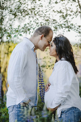 Fototapeta premium Husband and his pregnant wife stand face to face and smile